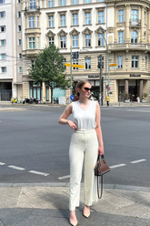 a lady in a white tank top and a pair of white pants